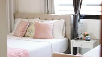 A bedroom with a bed, bedside table, lamp, and curtains.