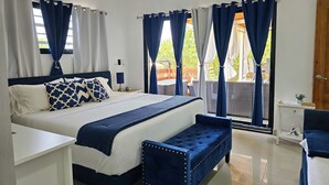 A bedroom with a bed, bedside tables, a bench, and a view of the outdoors.