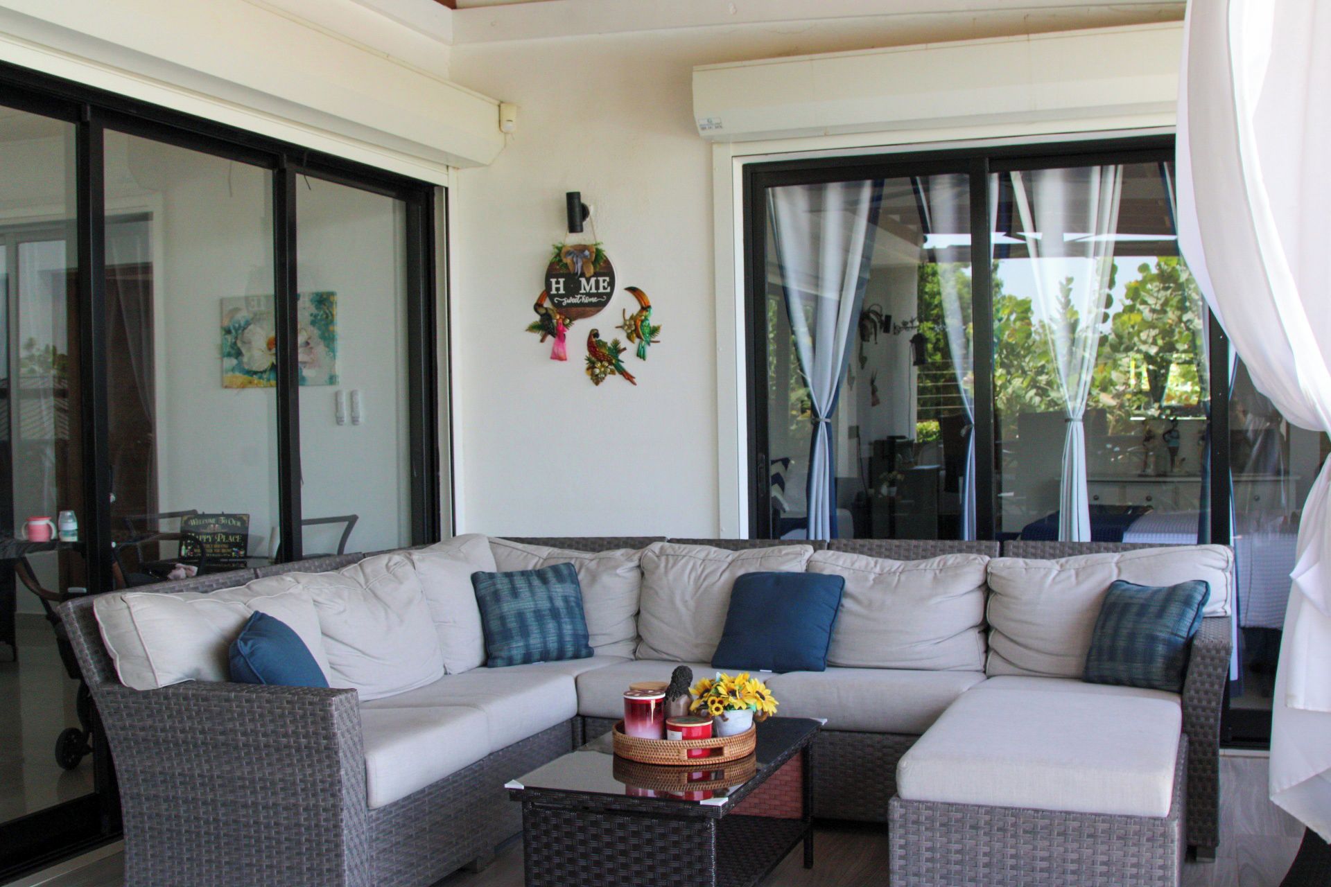 A modern living room with a sectional sofa, a coffee table with decorative items, and large windows with curtains.