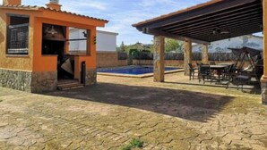 A covered outdoor area with a pool, stone flooring, and a small building with a chimney. - Martina House (Sant Julià d'Alfou)