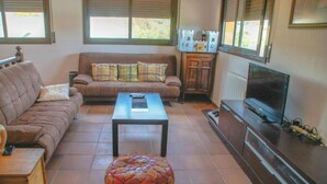 A living room with a sofa, ottoman, coffee table, TV, and a cabinet. - Martina House (Sant Julià d'Alfou)