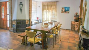 A dining area with a wooden table, yellow chairs, a fireplace, and a clock on the wall. - Martina House (Sant Julià d'Alfou)