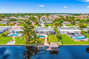A residential area with multiple houses, a swimming pool, and a dock extending into a body of water.