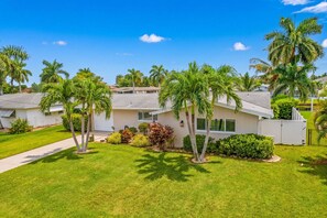 A residential area with houses, palm trees, and a well-maintained lawn.