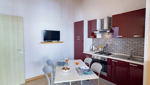 Une cuisine compacte avec un coin repas, un plafond en bois et un téléviseur fixé au mur.