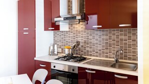 Une cuisine moderne avec des meubles rouges, une cuisinière en acier inoxydable et un dosseret carrelé.