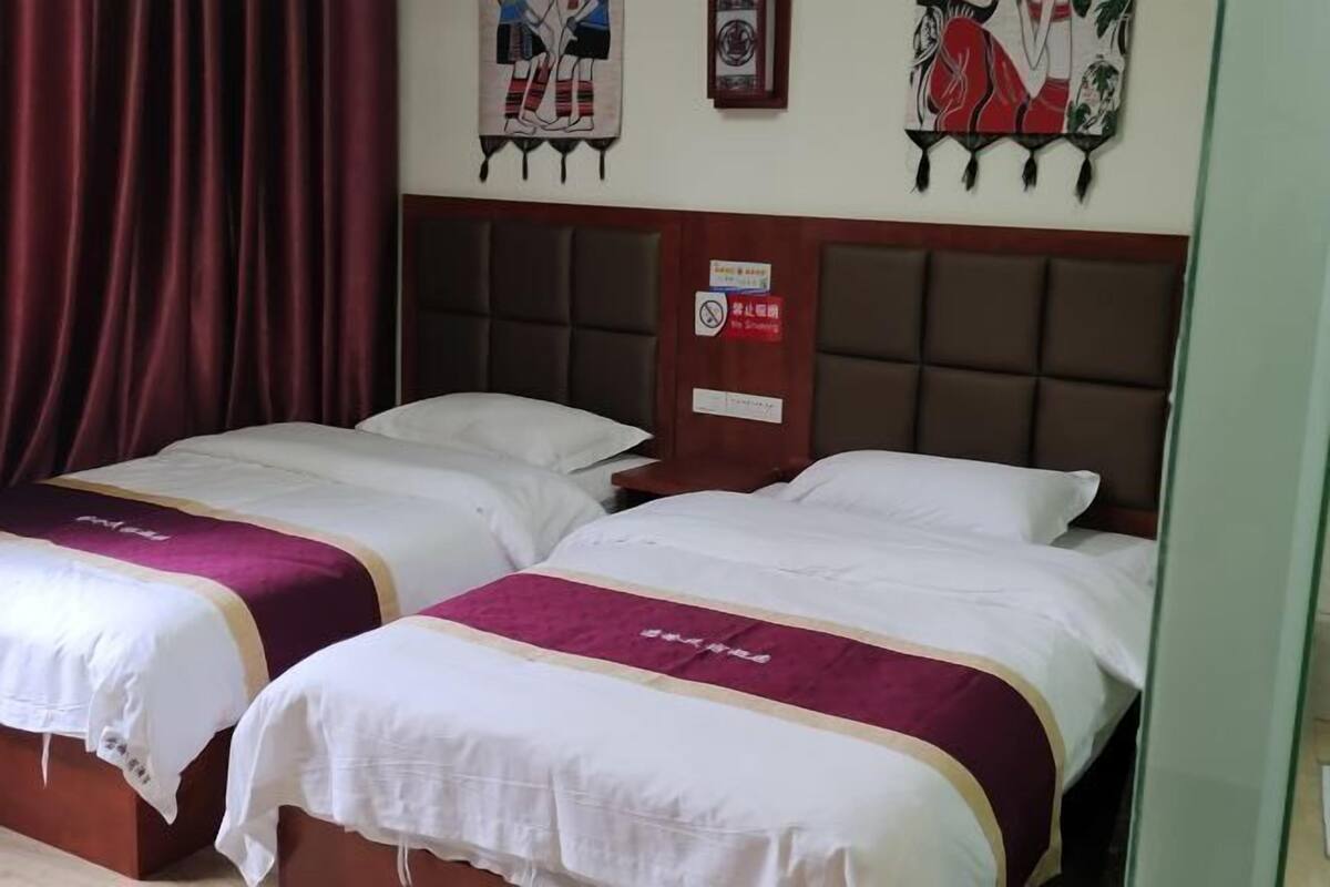 Two single beds with white and maroon bedding, a dark headboard, and artwork on the wall.