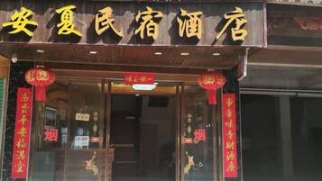 Entrada de hotel com elementos arquitetônicos chineses tradicionais, incluindo telhado com azulejos e lanternas vermelhas.