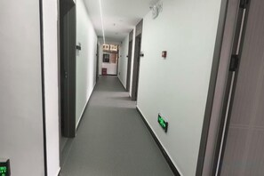 A narrow hallway with doors on both sides, a fire alarm on the right wall, and a light switch on the left wall. - Xijiang Anxia B&B (Leishan)