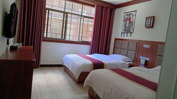 Quarto de hotel com duas camas, uma escrivaninha de madeira, uma janela com cortinas e obras de arte na parede.