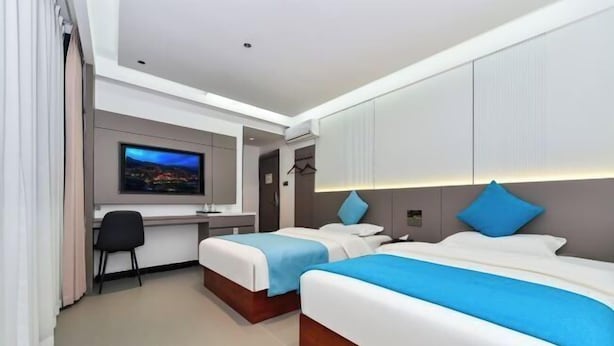 A hotel room with two beds, a desk, a TV, and a wardrobe. - Xijiang Anxia B&B (Leishan)
