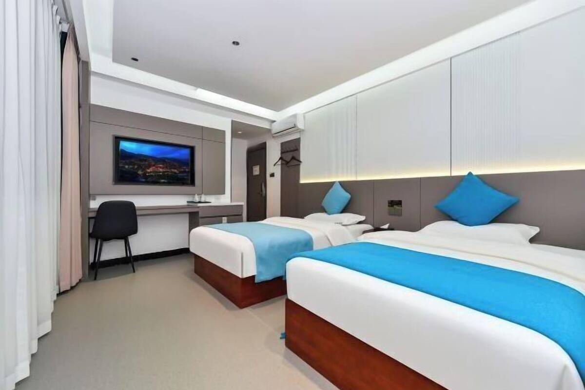 A hotel room with two beds, a desk, a TV, and a wardrobe.
