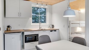 A compact kitchen with a dishwasher, oven, and a window above the sink.
