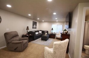 Relax in a spacious living room with a sofa, armchairs, and a flat-screen TV.