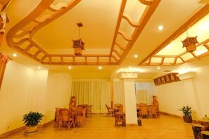 A spacious room with wooden flooring, multiple seating areas, and a high ceiling with decorative wooden beams. - Yunti Hotel (Lvchun)