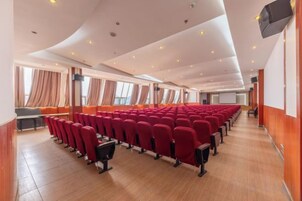 Un théâtre avec des rangées de sièges rouges, un plancher en bois et un plafond voûté.