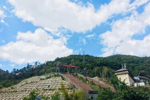 A terraced garden with a red structure on a hillside. - Yunti Hotel (Lvchun)