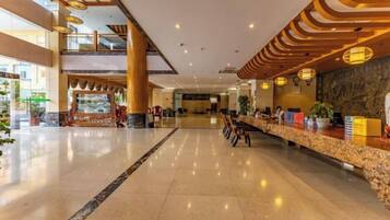 A spacious lobby with a reception desk, seating area, and a view of the outdoor area.