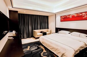 Una habitación de hotel moderna con cama, escritorio, silla y un amplio ventanal.