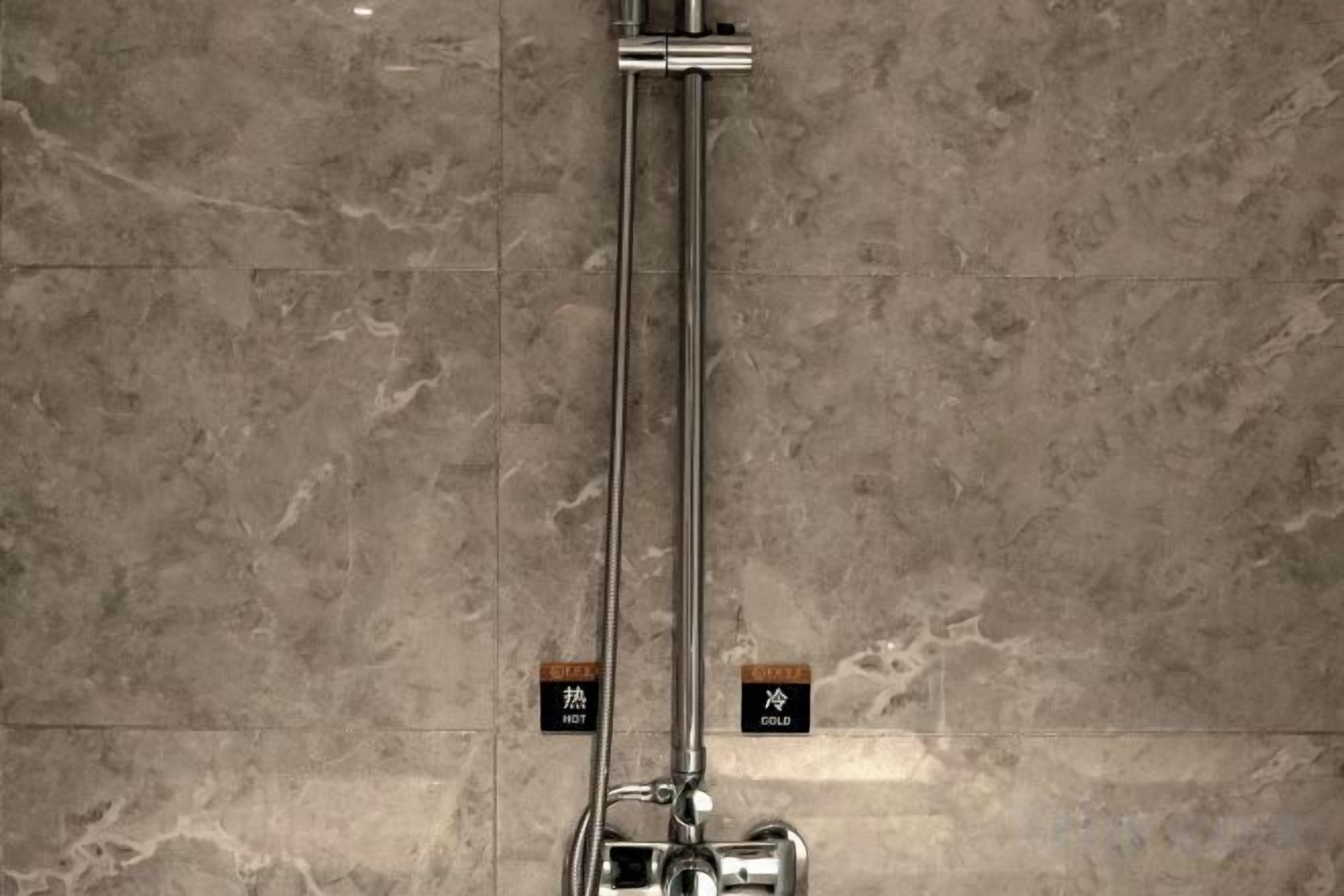 Ducha con grifería cromada y panel de control en la pared.