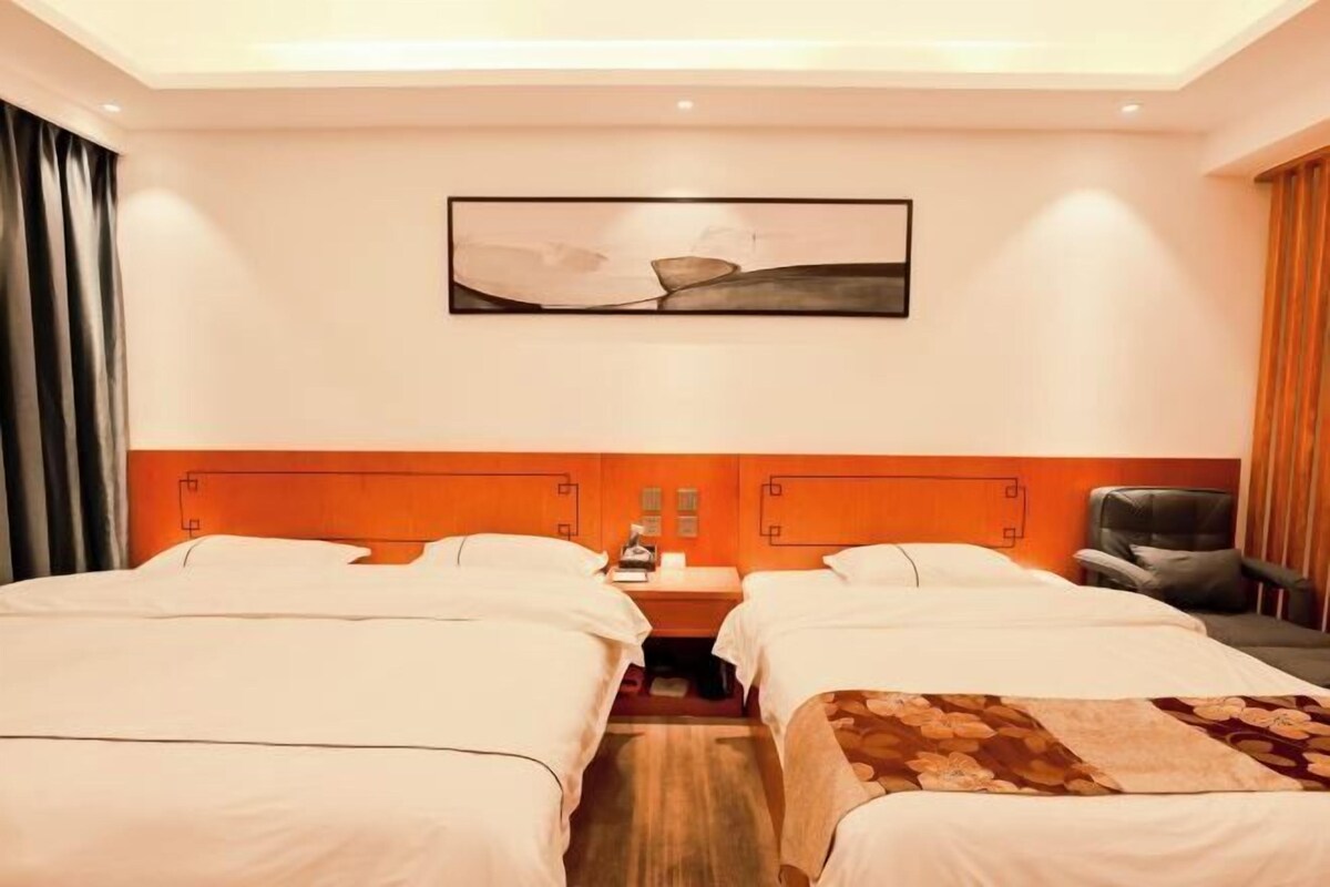 A hotel room with two beds, a nightstand, a chair, and a painting on the wall.