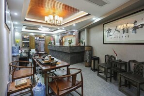 A hotel lobby with a reception desk, seating area, and a wall with calligraphy. - Yueshe Boutique Hotel (Huangyao Ancient Town) (Zhaoping)