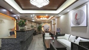 A reception area with a stone counter, a sofa, and a dining table. - Yueshe Boutique Hotel (Huangyao Ancient Town) (Zhaoping)
