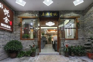 A boutique hotel entrance with a brick facade, glass doors, and potted plants. - Yueshe Boutique Hotel (Huangyao Ancient Town) (Zhaoping)