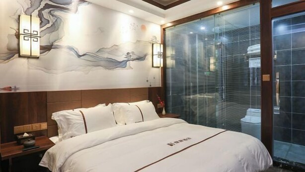 A hotel room with a large bed, a wooden headboard, a wall mural, and a sliding glass door. - Yueshe Boutique Hotel (Huangyao Ancient Town) (Zhaoping)