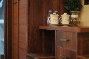 Un mueble de madera con un estante que contiene una tetera, una taza y un recipiente con hojas de té.