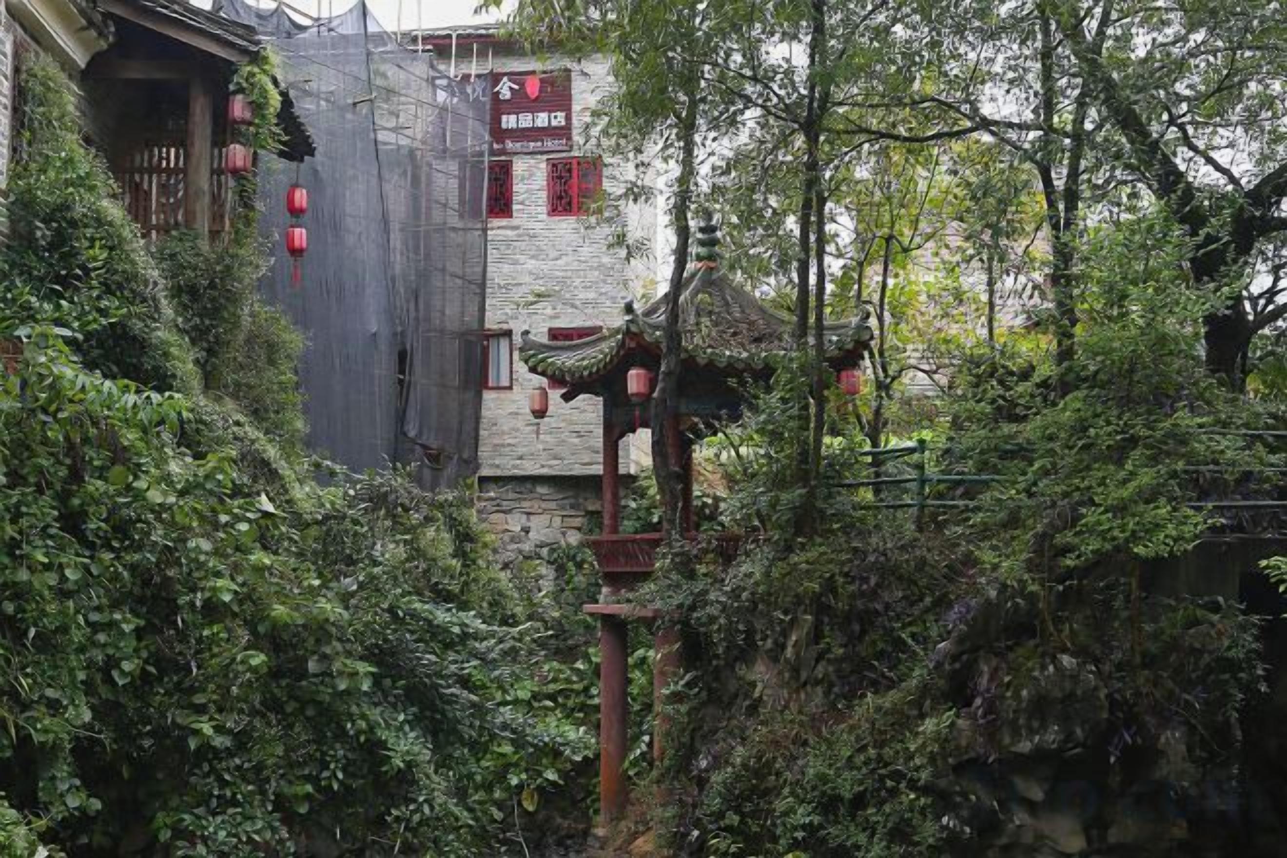 A traditional building with a stone facade, a wooden structure with a tiled roof, and a sign with Chinese characters.