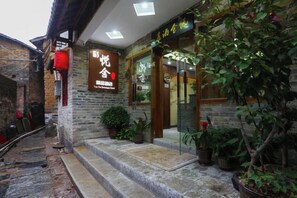 A building with a stone facade, a wooden door, and a potted plant in the entrance.