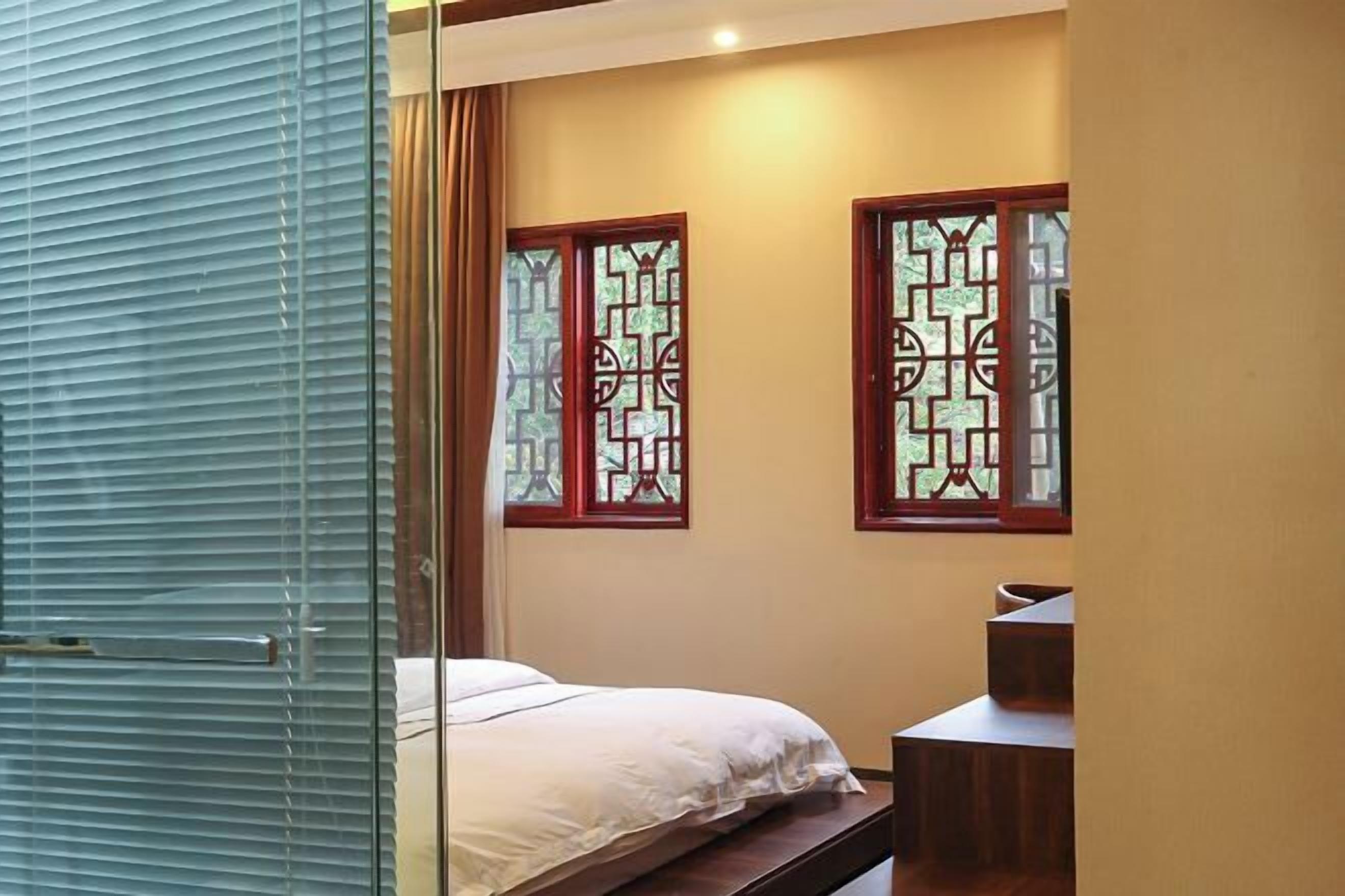 Une chambre à coucher comprenant un lit, un bureau et deux fenêtres ornées de vitraux décoratifs.