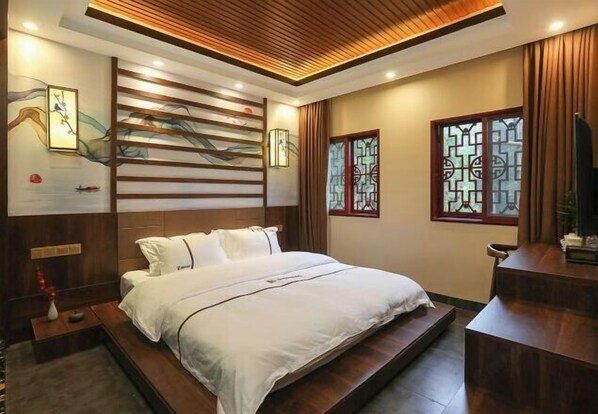 A bedroom with a bed, wooden paneling, a nightstand, and a TV.
