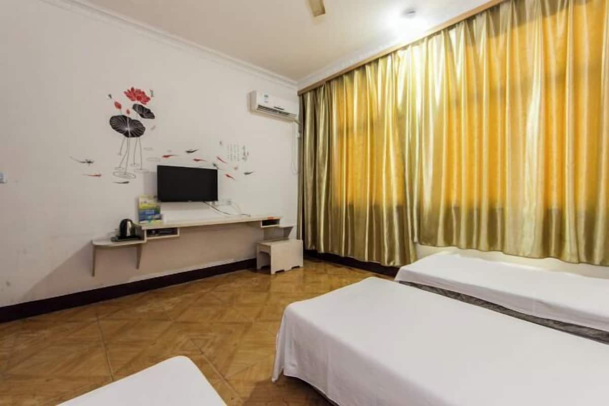 A hotel room with two beds, a TV, a small table, and a wall decoration.