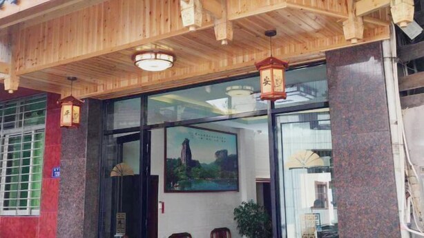 Un edificio tradicional de madera con techo de tejas, puertas de cristal grandes y un cartel con un paisaje.