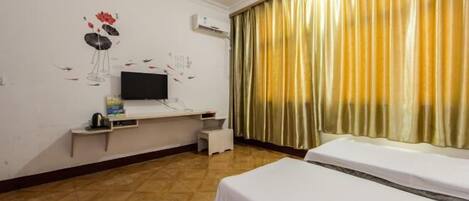 Quarto de hotel com duas camas, televisão, uma mesa pequena e um objeto decorativo na parede.