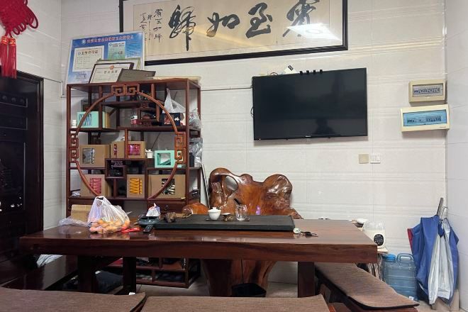 Una habitación con un escritorio de madera, un televisor montado en la pared y una pieza decorativa tradicional china.