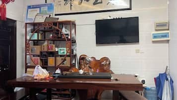 Una habitación con un escritorio de madera, un televisor montado en la pared y una pieza decorativa tradicional china.