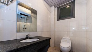 Un baño con lavamanos de granito, un espejo, inodoro y ducha.