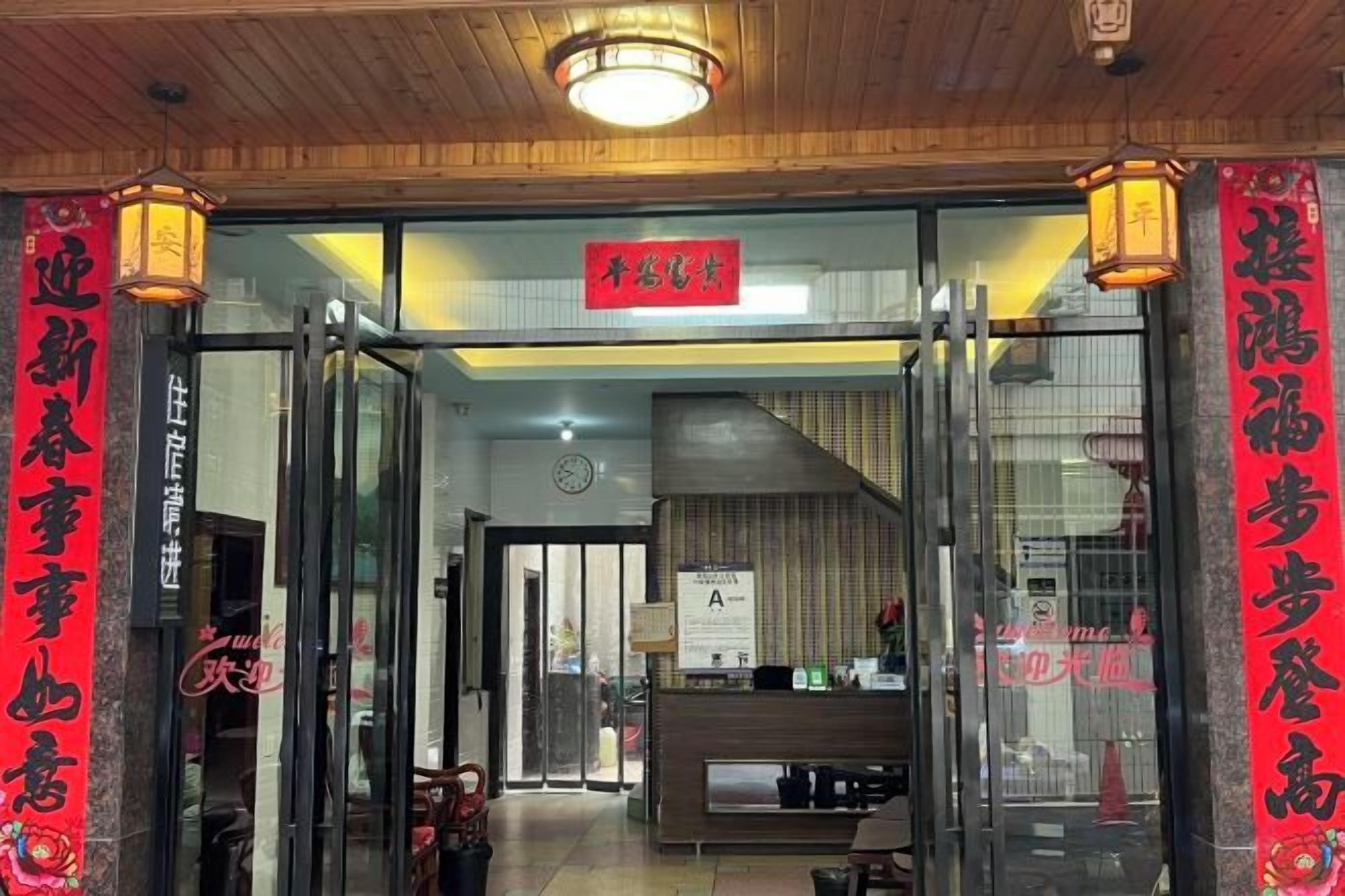 A restaurant entrance with glass doors, a reception desk, and a sign above the door.