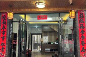 L’entrée d’un restaurant avec des portes vitrées, un comptoir d’accueil et une enseigne au-dessus de la porte.