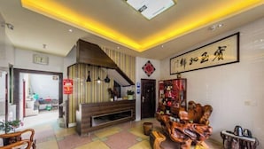 Una sala de estar moderna con una escalera, un mueble de entretenimiento de madera y una gran obra de caligrafía china en la pared.