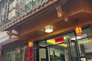 A traditional building with a wooden facade, a signboard, and a glass entrance. - Anping Hotel (Wuyishan)