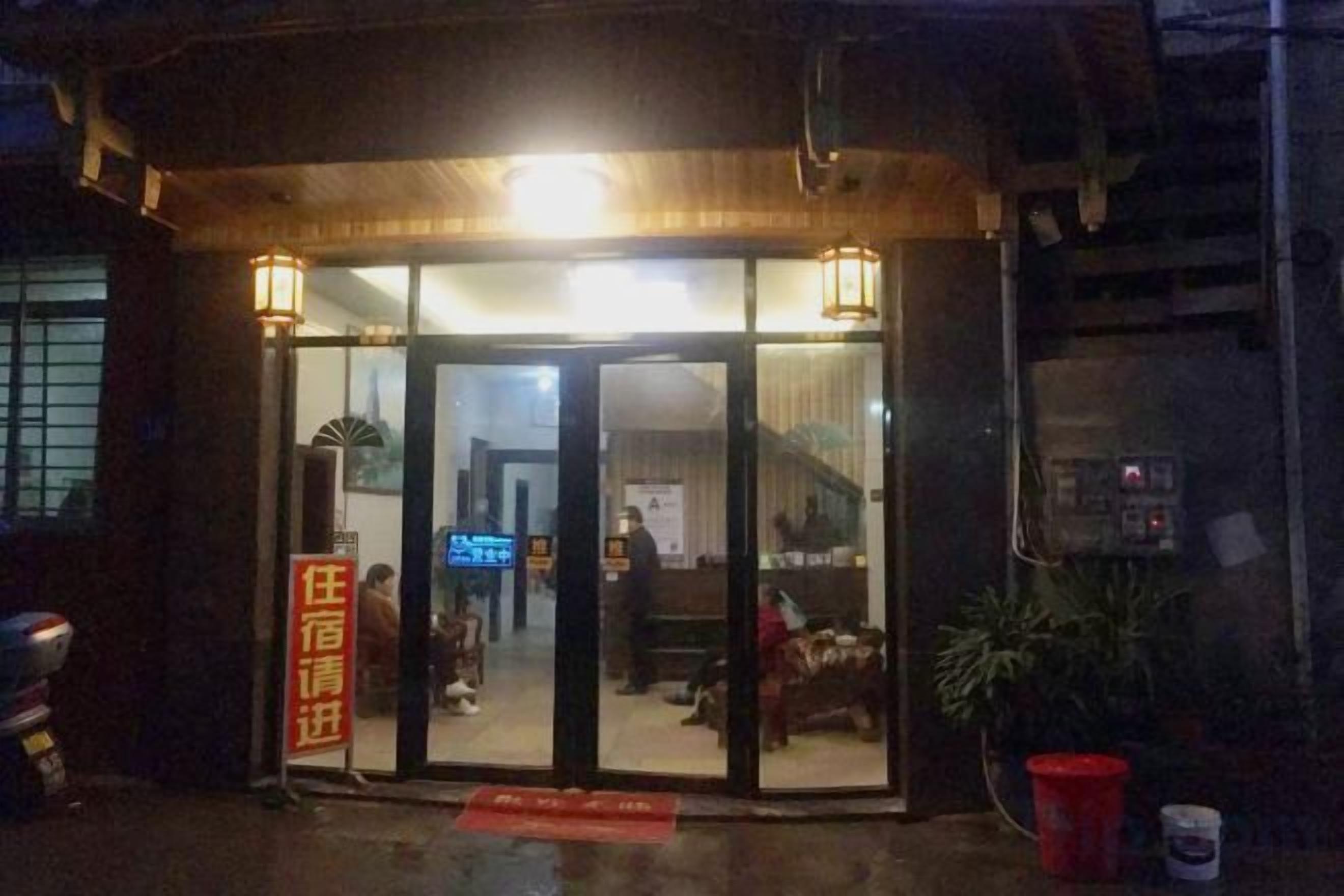 A hotel entrance with a glass door, a red mat, and a signboard.