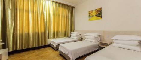 Una habitación de hotel con dos camas individuales, un ventilador de techo, un cuadro en la pared y una cortina.