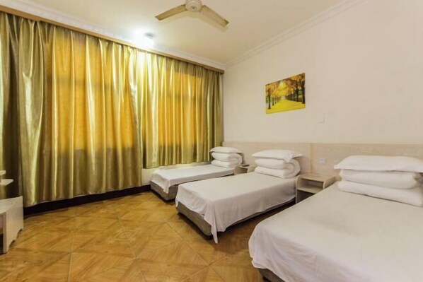 A hotel room with two single beds, a ceiling fan, a painting on the wall, and a curtain. - Anping Hotel (Wuyishan)