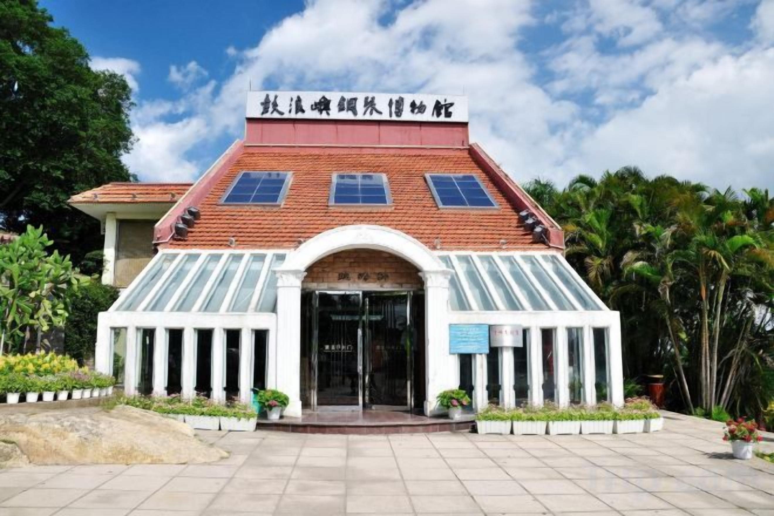 A building with a red roof, a glass entrance, and a sign in a foreign language.