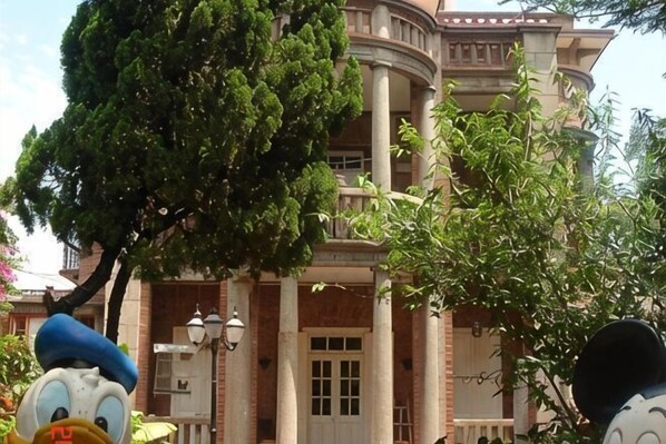 A building with a curved facade, large columns, and a tree in front. - Chuanwu Old Villa Family Hotel (Xiamen)