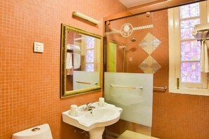 A bathroom with a tiled wall, a white sink, a mirror, and a glass shower enclosure. - Chuanwu Old Villa Family Hotel (Xiamen)